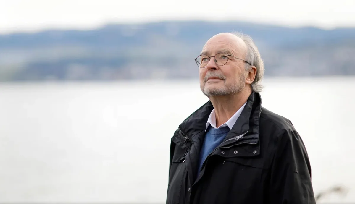 Ein Mann steht am See und schaut in den Himmel. 